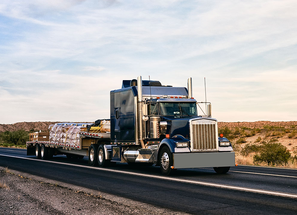 Flatbed truck transporting various types of freight on USA highway