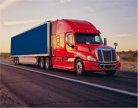 Truckload shipment being carried across the USA on red and blue tractor trailer